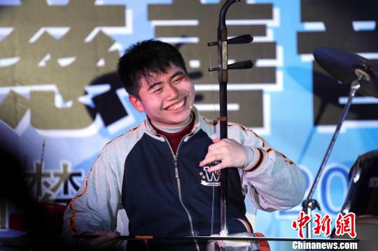 魏俊一边拉着二胡一边踩着脚下的架子鼓，演奏之中还扬起灿烂的招牌笑脸。刘占昆 摄