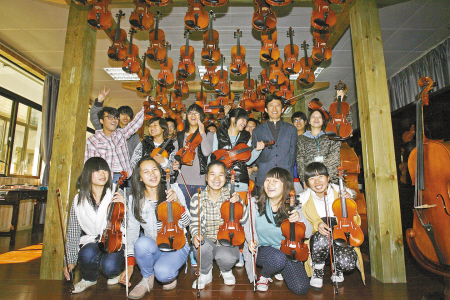 学生们拿着自己的小提琴与老师合影。