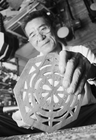 林朱法在精心雕琢一扇大胡的后花窗。