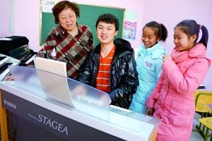 王老师的大学生弟子正给王老师的小学生弟子弹一曲。