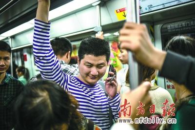 清晨拥挤的地铁上，陈伟坚用手机听时间报音。