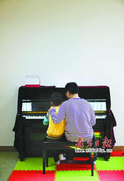 陈伟坚和自闭症儿童一起弹钢琴。