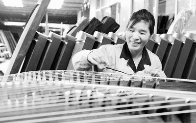 近年来，河南省兰考县堌阳镇徐场村利用本地生产桐木的资源优势，大力发展乐器制造业，全村拥有41家乐器生产企业，他们纯手工制作的古筝、琵琶等乐器深受市场青睐，畅销世界各地。图为5月8日，徐场村村民王排玲在调试古筝。