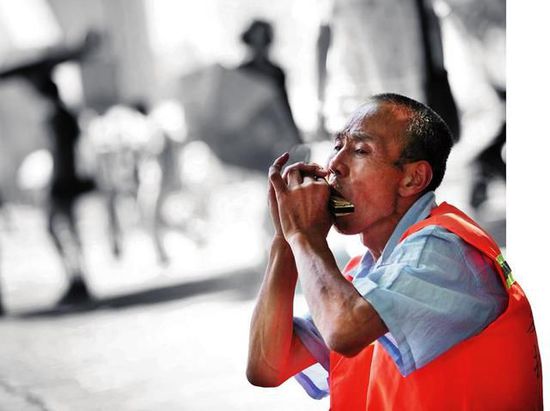 六旬保洁员车祸意外丧子 吹奏口琴排解忧伤(图)